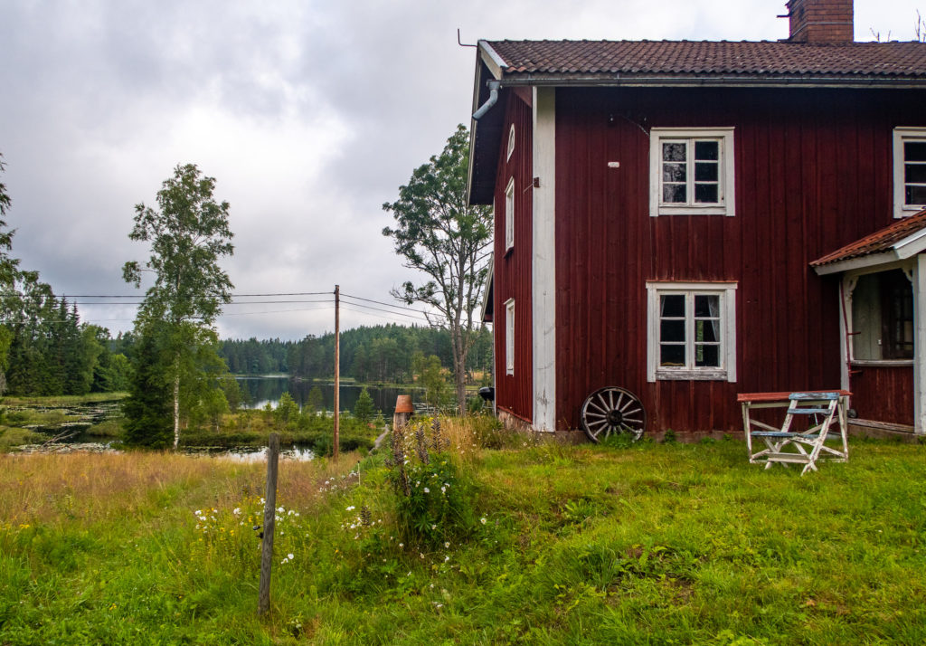 Röd stuga med sjö bakom