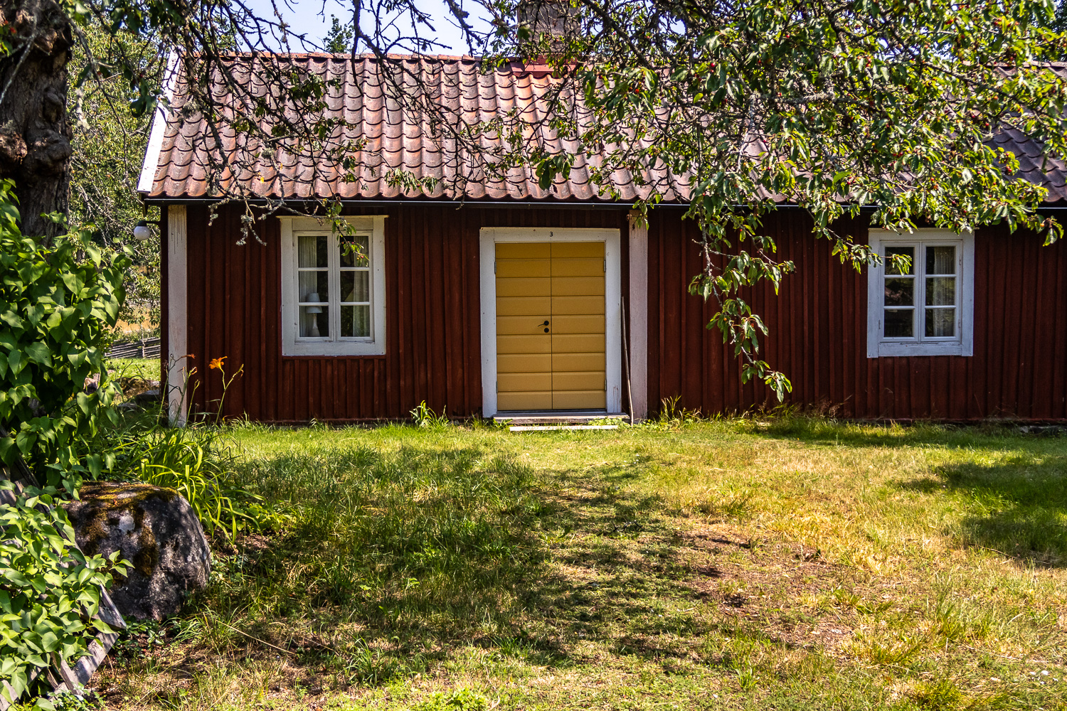 Gul dörr på gammal röd träbyggnad i Stensjö by
