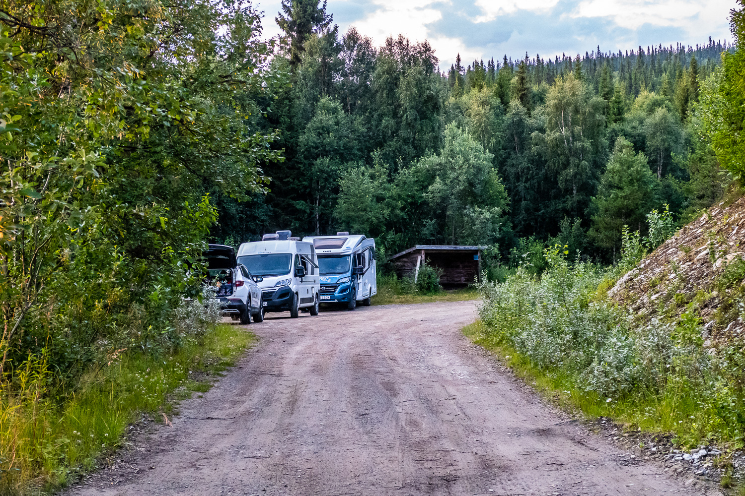 Husbilar och en bil parkerade på grusplan