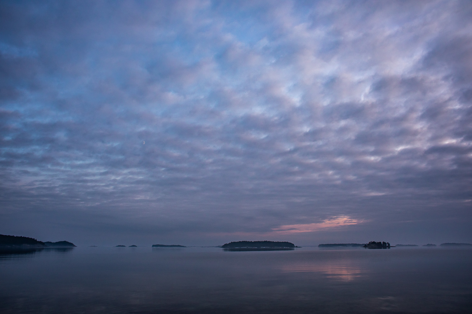 SKymningen färgar molnen på himlen lila och blå