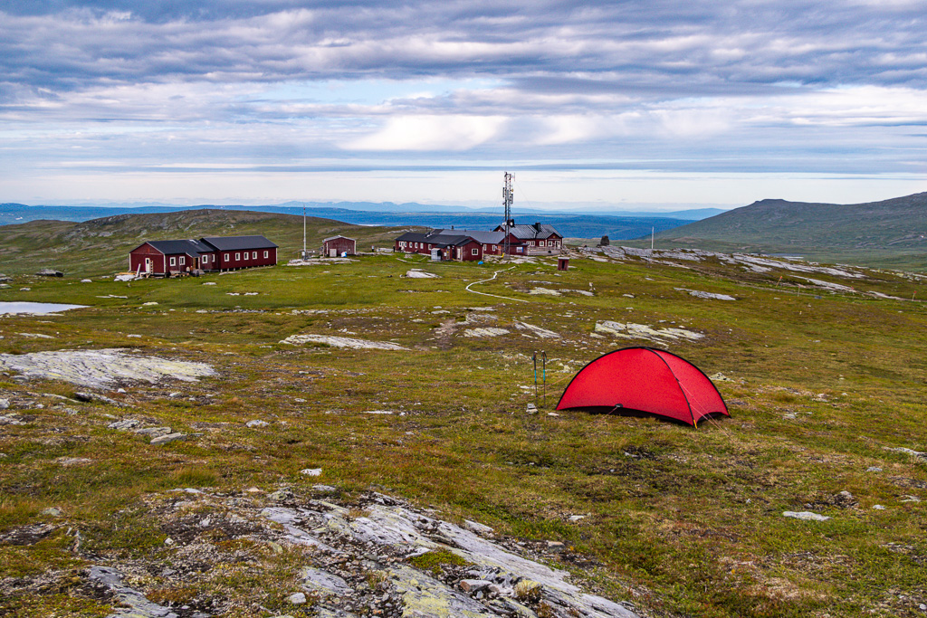 Tält i förgrunden med Blåhammarens fjällstation bortanför