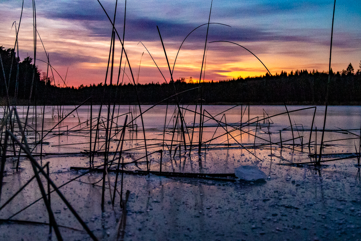 Vacker solnedgång över isbelagd sjö.