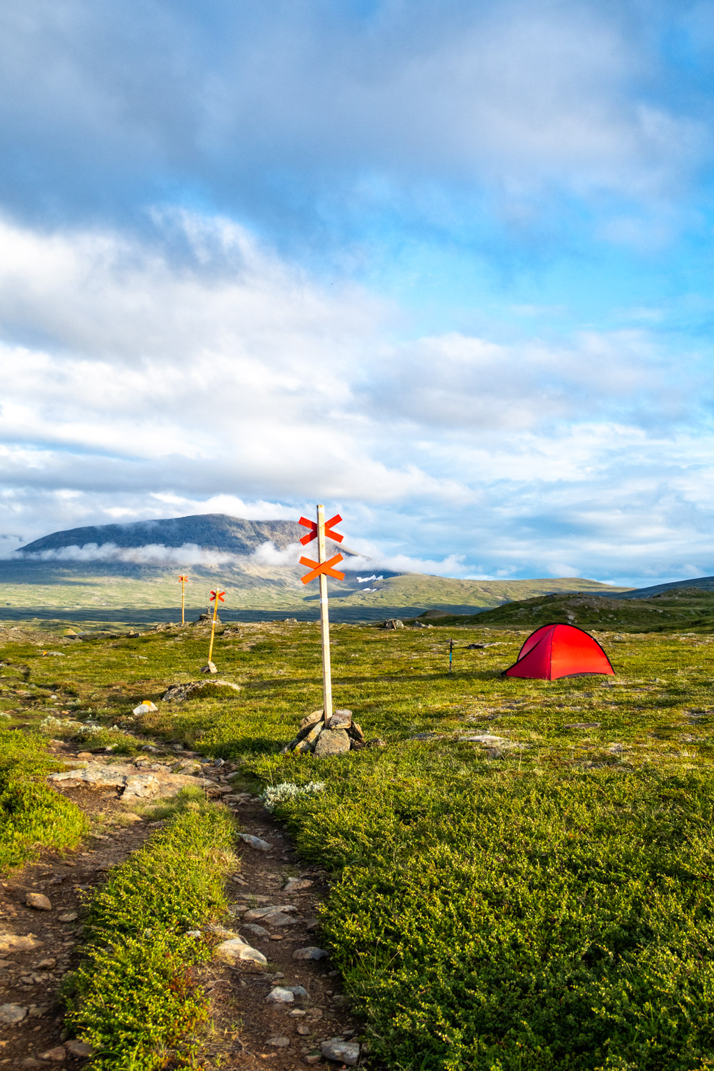 Tält uppsatt bredvid led i fjällen