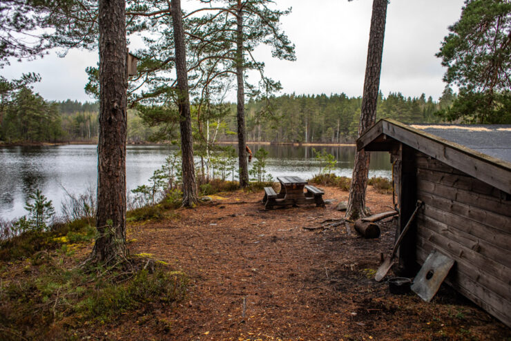Delar av vindskydd fotat från sidan, med vy över sjö.